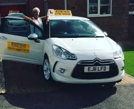 Photo of a white vehicle with driving instructor yellow signage on roof and door